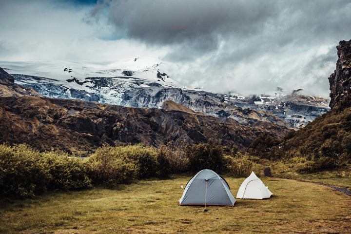 Tents and shelters pitched below a glacier
