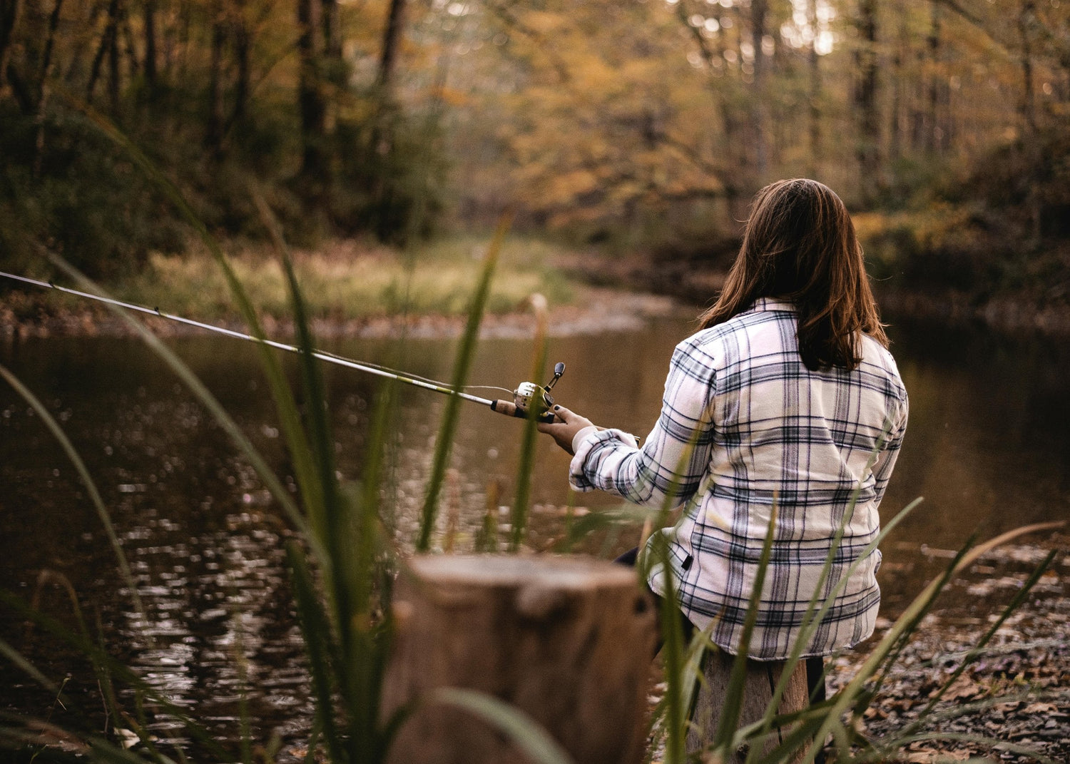 Angler working a spinning reel along a river bank